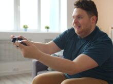 Happy adult engaged in video gaming, sitting on a couch indoors.